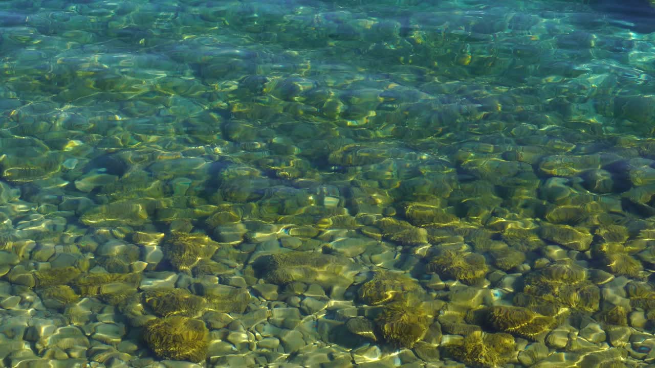 청록색 투명한 물에 햇빛을 반사하는 자갈이 있는 다채로운 호수 바닥