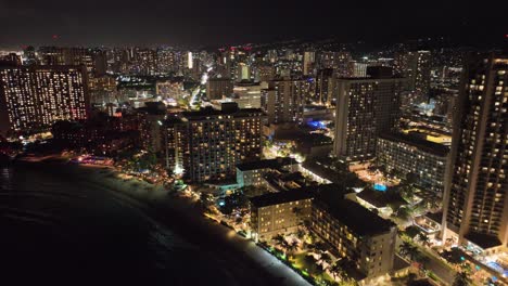 Imágenes-Nocturnas-De-Drones-Aéreos-De-30-Fps-Del-Tráfico-De-La-Franja-De-Waikiki-Coches-Luces-De-La-Ciudad-Palmeras-En-El-Horizonte-De-Honolulu-Hawaii