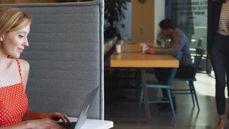 young businesswoman at desk in cubicle in modern office work space using laptop