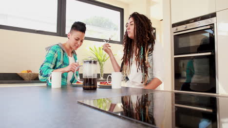 Smiling-lesbian-couple-eating-breakfast-together-in-the-kitchen