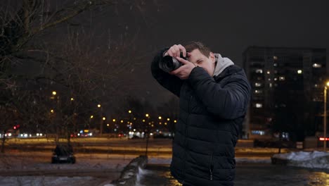 young caucasian male photographer taking photos in city at night