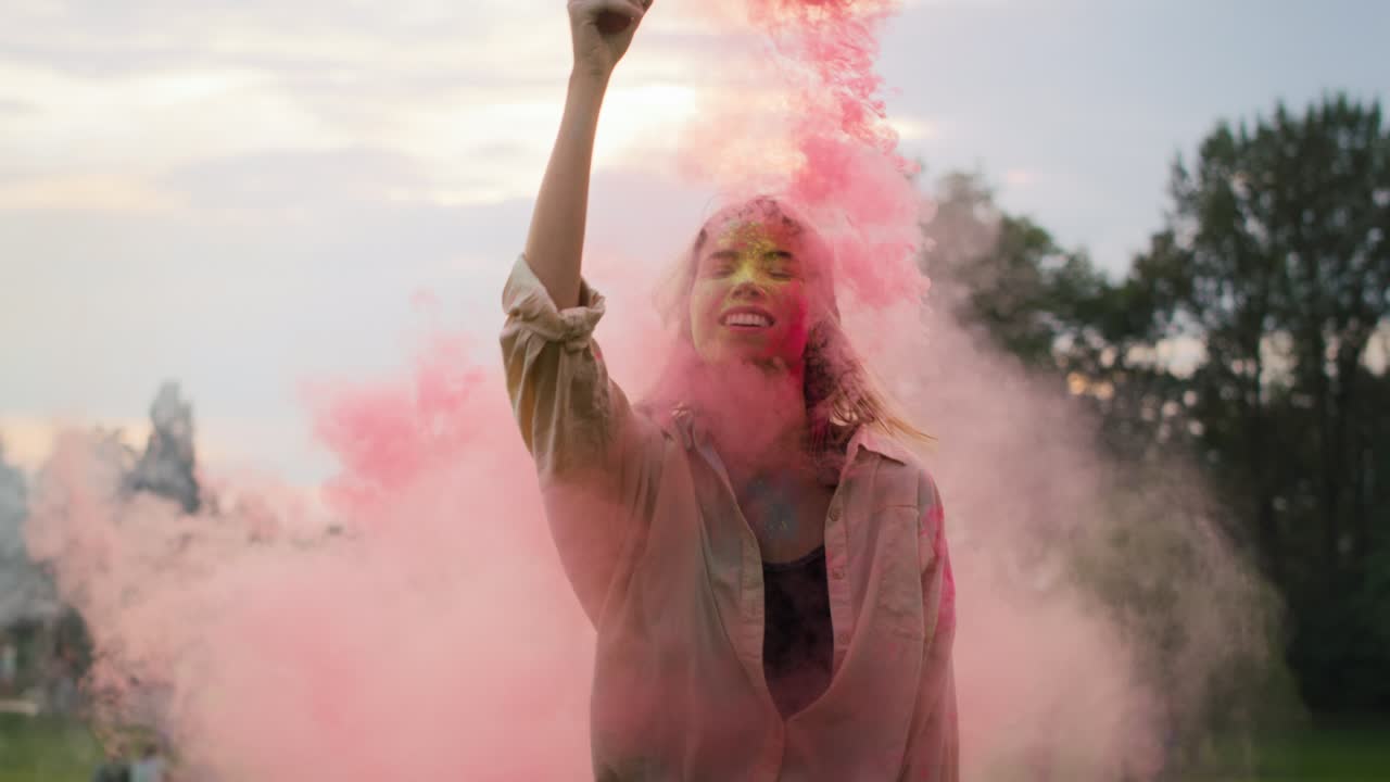 Donna caucasica che balla con fumogeni colorati al Festival Holi. Ripreso con telecamera RED Helium in 8K.