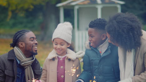 family having fun with sparklers in autumn garden at home - shot in slow motion