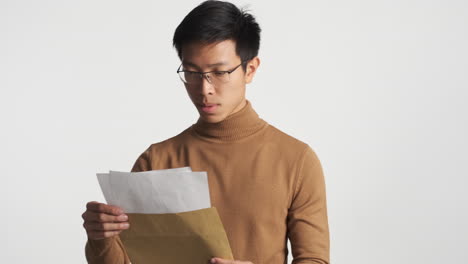 asian man oppening an envelope and reading content.