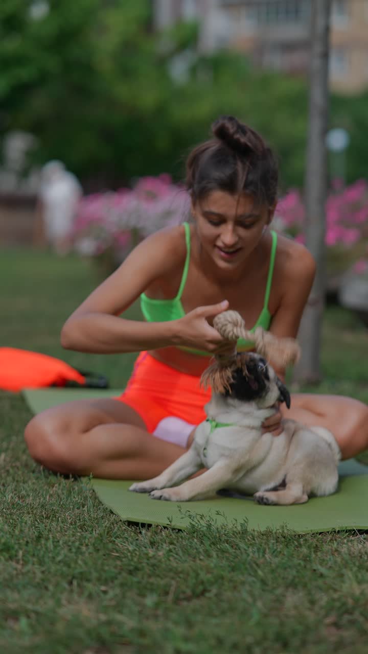 mujer jugando con perro pug en el parque