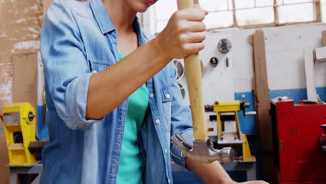 carpintero sonriente quitando un clavo en una tabla de madera