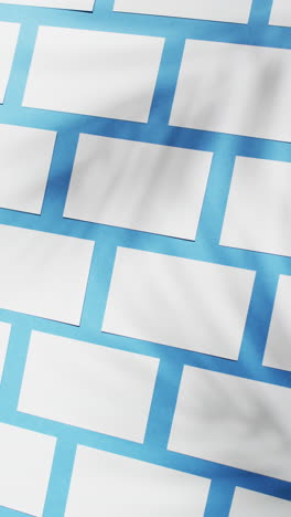 vertical video of white business cards arranged on blue background, copy space, slow motion