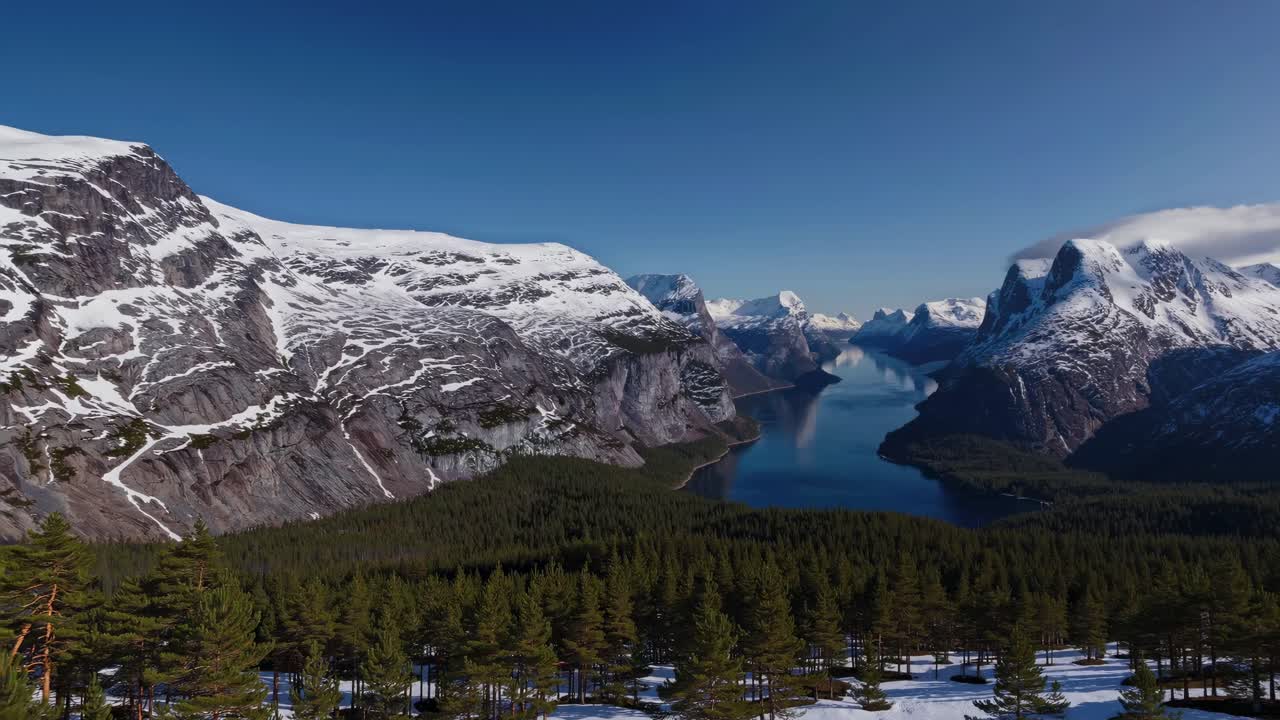 Aerial video view of a serene mountain landscape with snow-capped peaks and a winding river