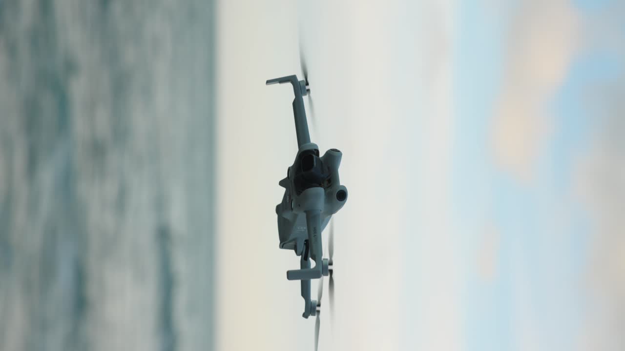 video vertical de un dron volando sobre el océano luchando contra el viento