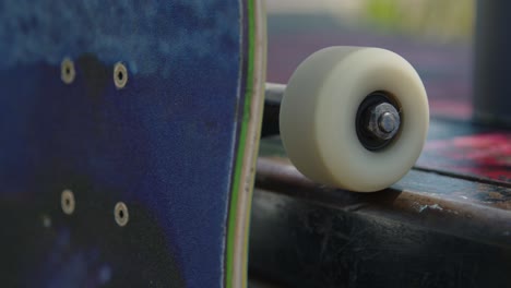 close-up panning shot of a skateboard resting on a ledge at the skatepark, with the wheel spinning smoothly