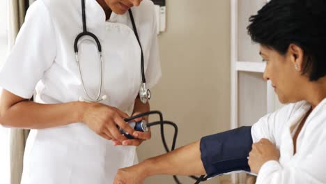 female doctor measuring blood pressure of mature woman in bedroom 4k