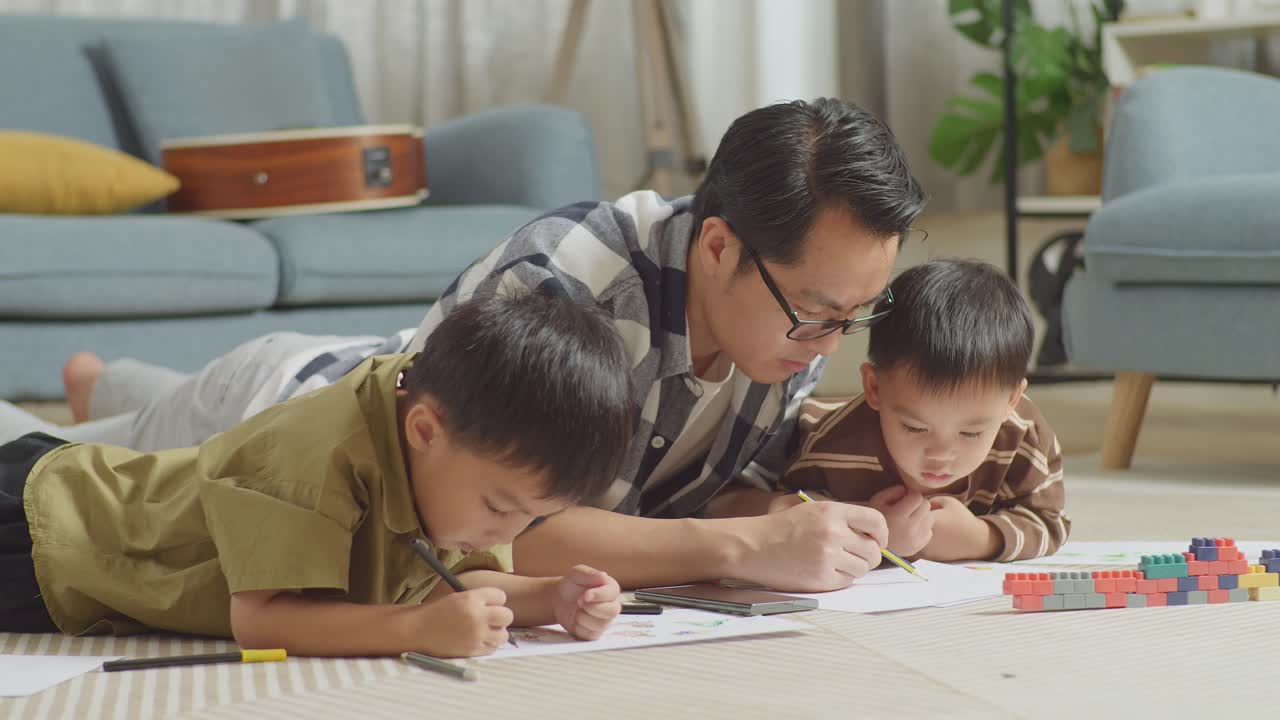 플라스틱 장난감 벽돌로 방 바닥에 누워있는 아시아 아버지와 아들의 클로즈업 스마트 폰을보고 집에서 함께 그림을 그리고 있습니다.