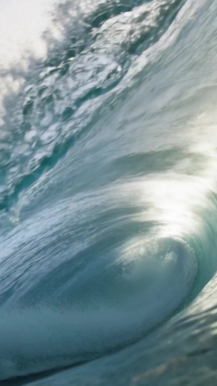 Vertical video: Moving curling ocean wave carrying camera through barrel at surf zone, lip curling