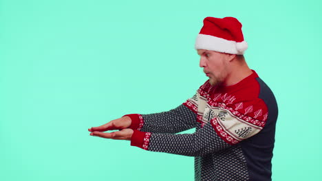 hombre lleva suéter de año nuevo rojo ciervo mostrando los pulgares hacia arriba y señalando en el espacio de publicidad en blanco