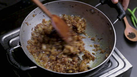 frying finely chopped onion in a deep cooking pan, adding ginger garlic paste