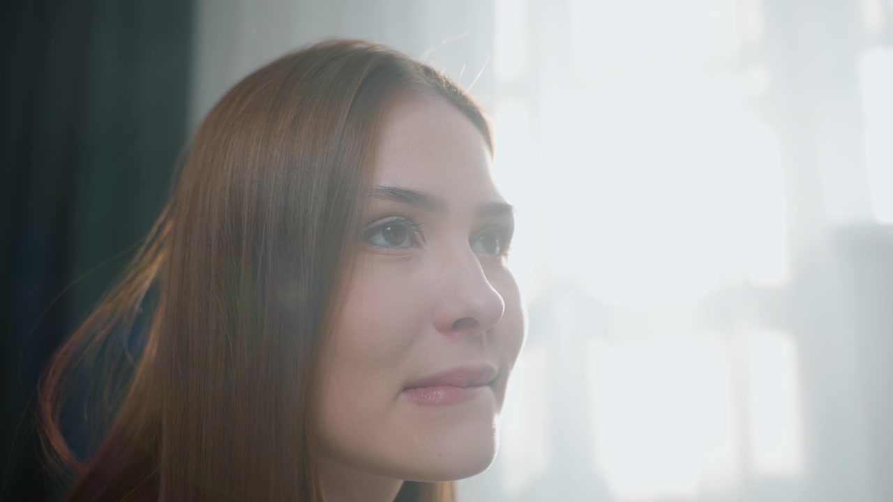 Studente in controluce sorridente, speranzoso per i progressi in grammatica, gli occhi brillano verso la finestra, leggero morso al labbro, bagliore caldo sul viso, celebrazione silenziosa dopo la sessione di tutoraggio, momento intimo di apprendimento a casa