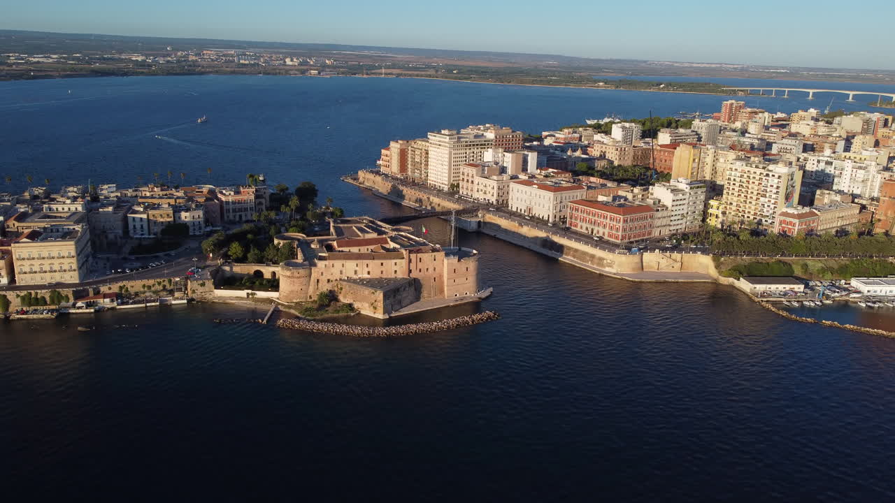 Taranto, Italy On Sunny Day, With Aragonese Castle, Historic Old Town Buildings And Bridges In View. aerial panning shot