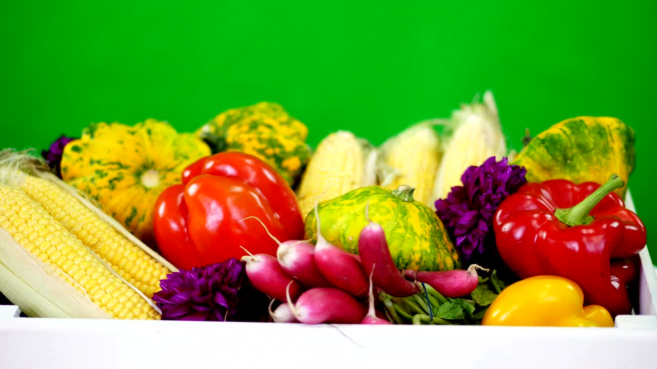 close-up, a white wooden box with the harvest, different fresh vegetables, corn, pepper, radish, zucchini, patissons. on green background, in studio, Healthy food to your table, Healthy nutrition