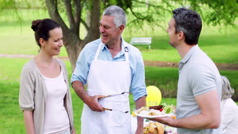 abuelo feliz sirviendo hamburguesas en una barbacoa familiar