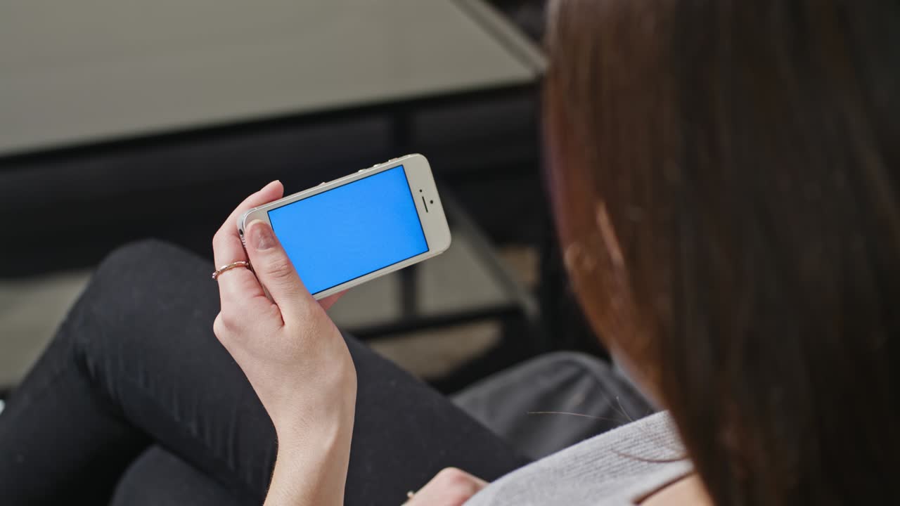 한 여성이 파란 화면의 스마트폰을 들고 있다.