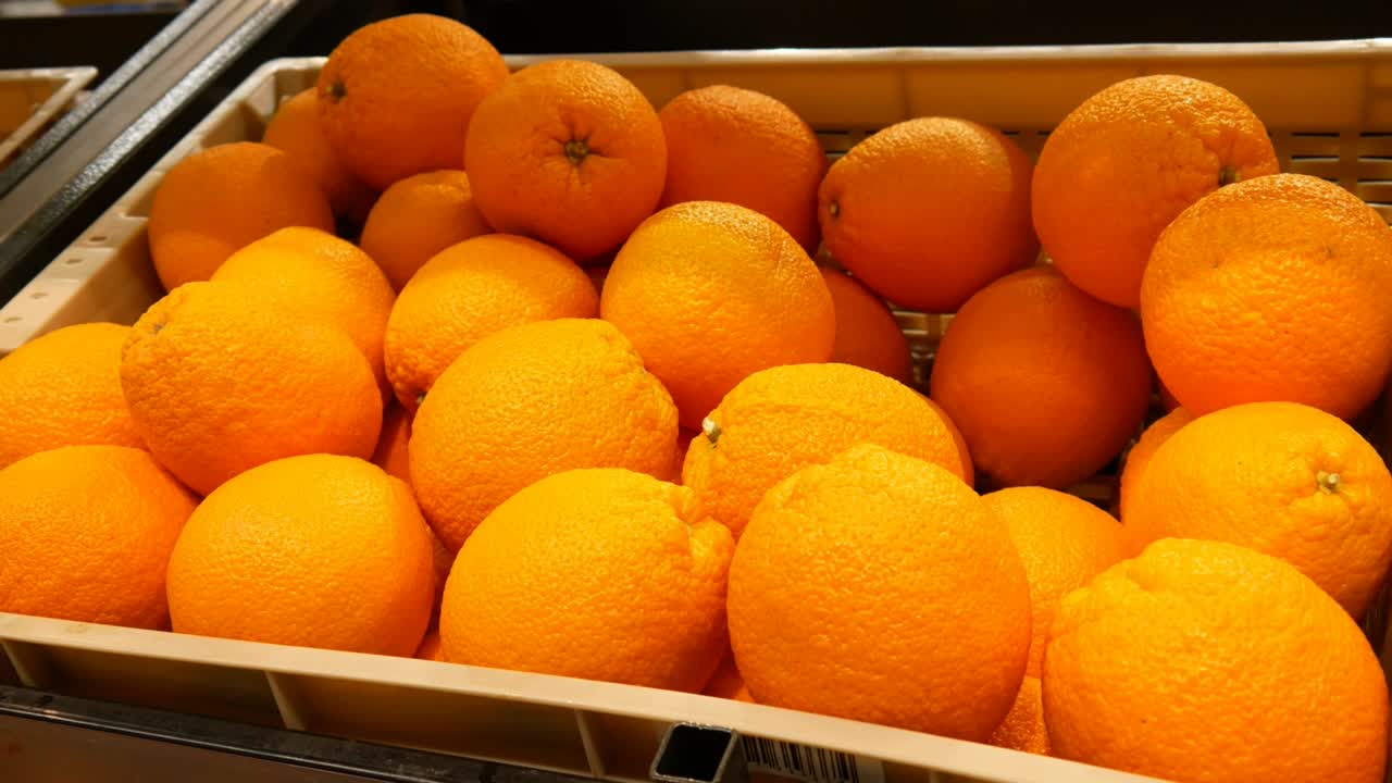 primer plano de muchas naranjas maduras en una canasta de comercio y una mano masculina toma una