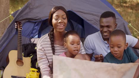 Family-looking-at-map-card-in-front-of-a-tent