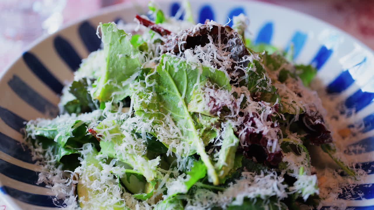 Close up of a salad with leafy green and grated parmesan on top