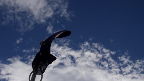 looking up at australian national flag blowing on pole during windy day with cloudy sky