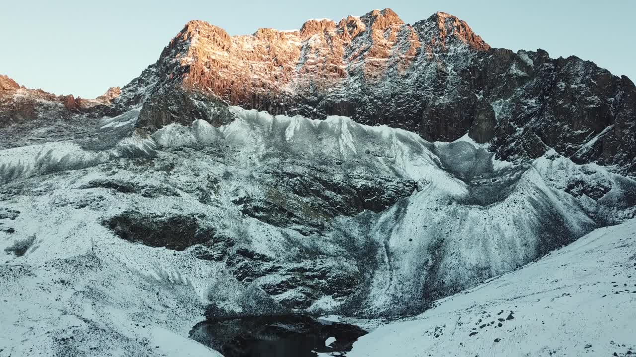 Aéreo, inclinação para baixo, tomada de drone das montanhas rochosas dos Andes e um lago nevado, ao nascer do sol, em Pitumarca, Peru, América do Sul