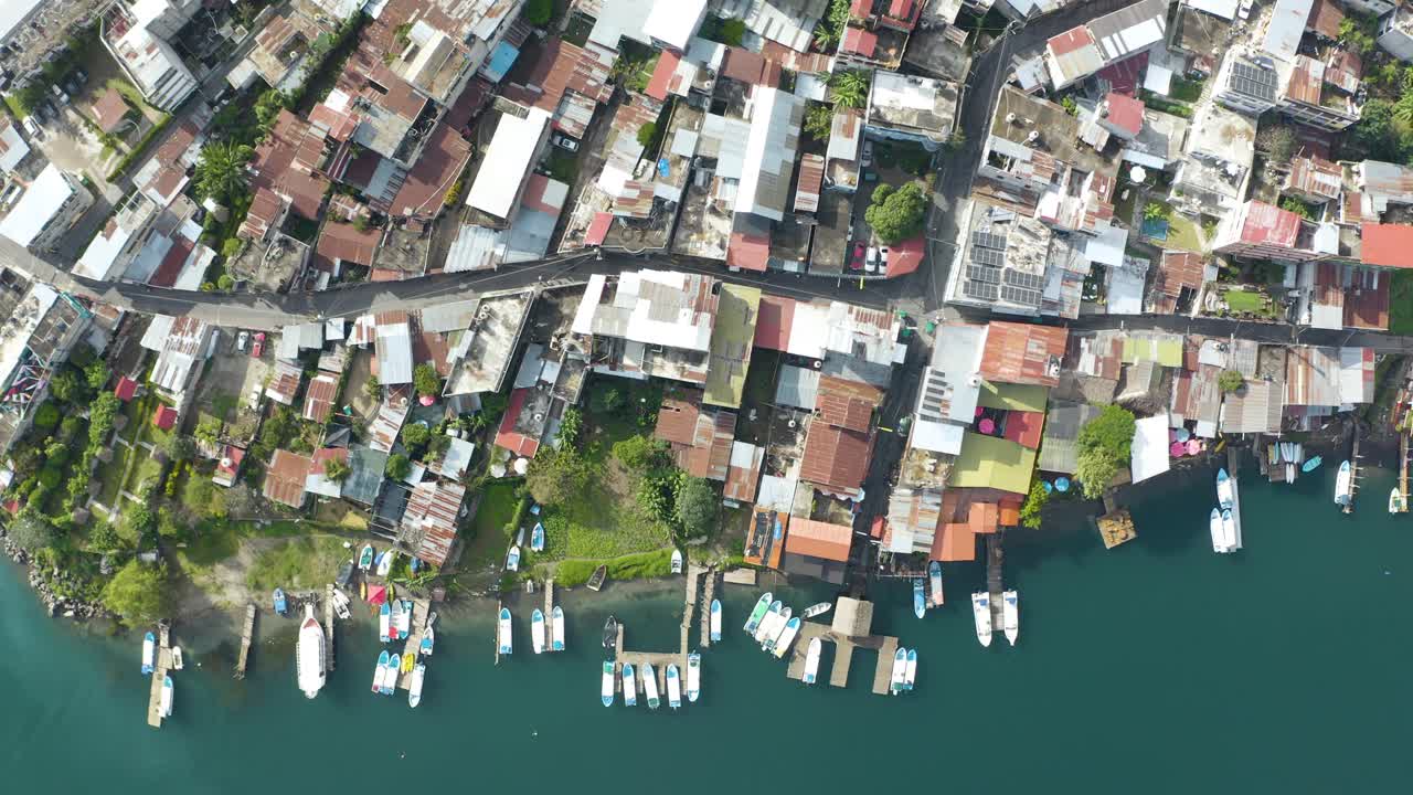 drone de arriba hacia abajo desciende en el pueblo costero por el lago aitlan guatemala con barcos atracados en el muelle
