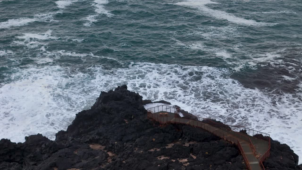 Aerial backwards shot showing waves of atlantic reaching Brimketill coast in Iceland. Wide shot.