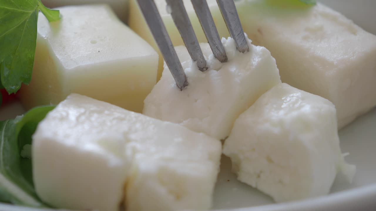 primer plano de un tenedor recogiendo un pedazo de queso feta