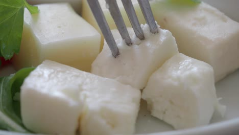 close-up of a fork picking up a piece of feta cheese