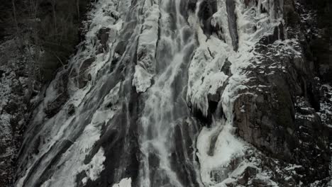 Cascada-Cae-En-Una-Exuberante-Montaña-Rocosa-Con-Nieve-Derretida-En-Vallee-Bras-du-nord,-Canadá---Tiro-Inclinado-Hacia-Arriba