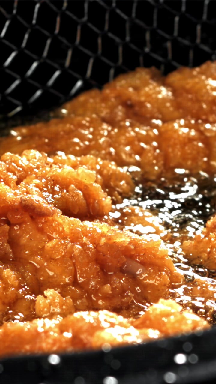 熱い油で揚がるきつね色のフライドチキン。