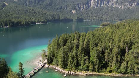 Ruhiger-Und-Malerischer-See,-Umgeben-Von-Bäumen-Und-Bergen,-Die-Eine-Idyllische-Landschaft-Schaffen.-Kurze-Steinbrücke-Zwischen-Den-Inseln,-Damit-Wanderer-Und-Autos-Die-Helleren-Stellen-über-Dem-See-überqueren-Können