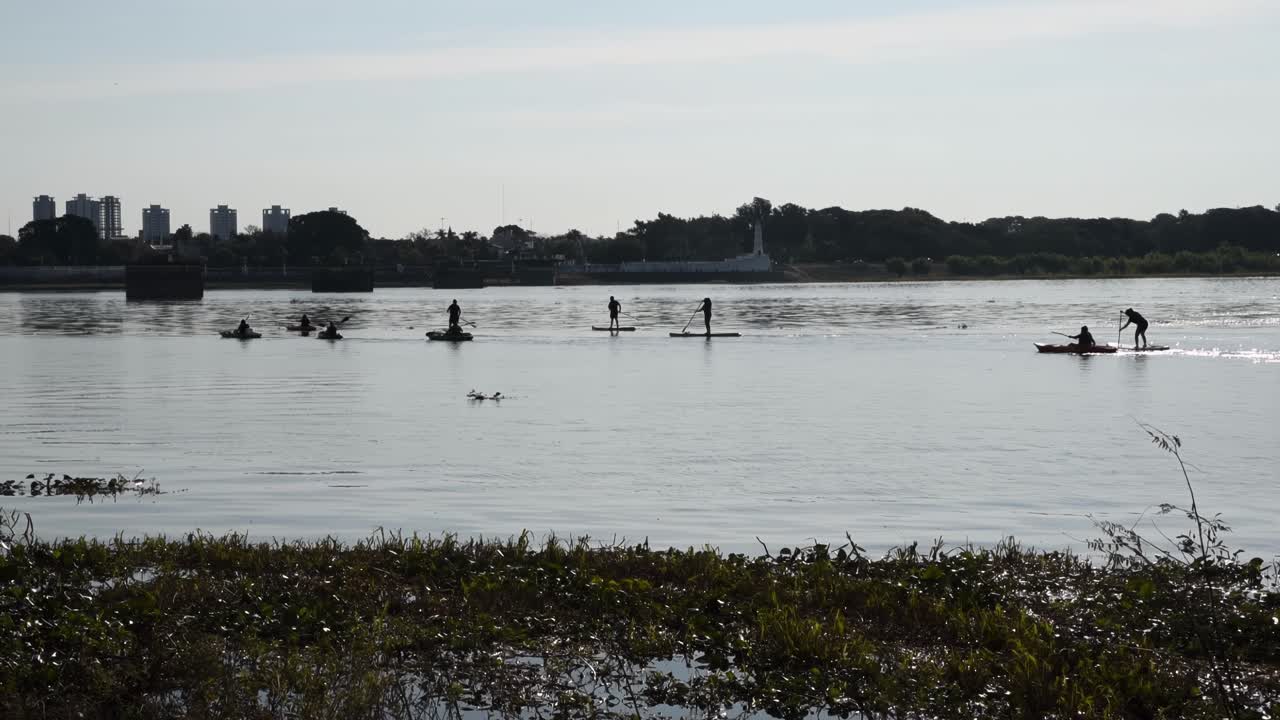 Folk, der sejler i kajak og paddleboard på floden omgivet af vandplanter