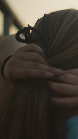 vista trasera de la joven ajustando su cabello durante el anochecer, luz suave y cálida iluminando su silueta, creando una atmósfera serena de la noche con fondo borroso y belleza natural