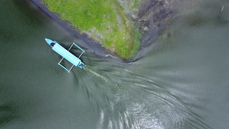 aerial footage of a blue motor boat travelling down a narrow lake