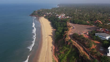 aerial shot of varkala beach with trees and buildings in the shore