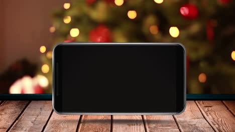 animation of blank smartphone screen with out of focus christmas tree on wooden surface