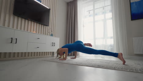 una mujer joven en aislamiento hace yoga en casa en un tapete en su apartamento
