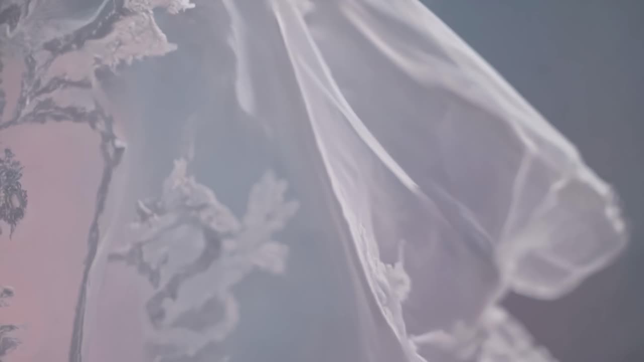 Close-up video of delicate lace fabric flowing gently, captured from a side angle