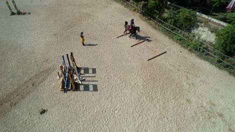 drone flying backwards captures a failed first horse jump over ground bars while the trainer watches in front of obstacles
