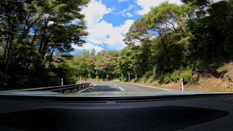 el conductor de pov conduce un coche en la carretera costera hacia la península de coromandel en verano en nueva zelanda.