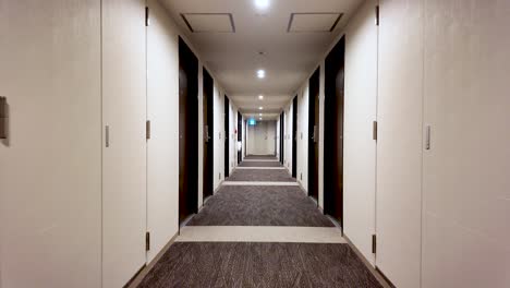 long corridor stretching through an empty hotel, featuring numerous doors and a plush carpet underfoot, creating a serene atmosphere