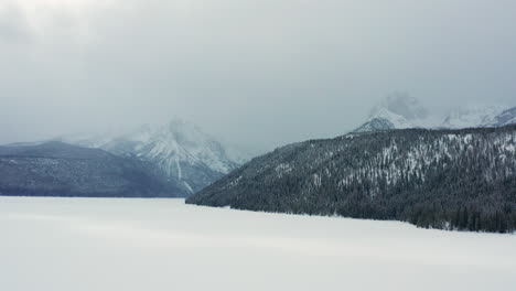 aerial over redfish lake in winter with sawtooth mountains behind in clouds