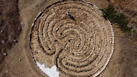 aerial view of a person walking through a stone maze art installation, finding the future in avdimou beach