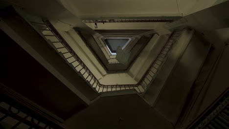 bottom view of the stairs and many floors with old fashioned iron and wooden railings. stock footage. plastic bag flying along the floors of an unusual triangular shaped house entrance