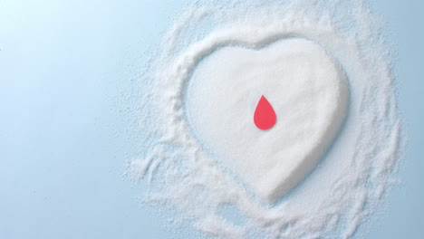 cerca de la gota de sangre sobre el azúcar en forma de corazón sobre fondo azul, cámara lenta.